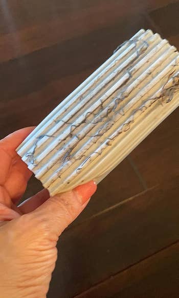 Person holding the duster sponge that is covered in dust and grime