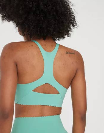 Person wearing a mint green sports bra with a cut-out design, viewed from the back