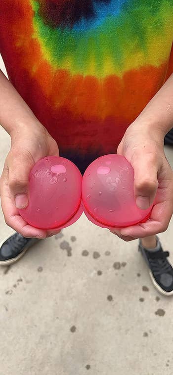 reviewer's child holding two pink water balloons