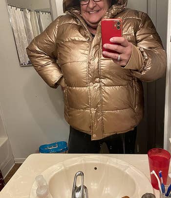 a reviewer wearing the coat in gold meetallic 