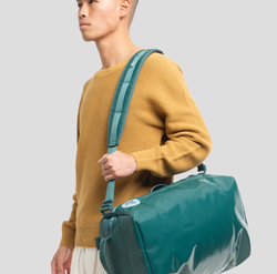 Model with the mini to-go bag slung over their shoulder in color Enfant Précoce Jasper Green