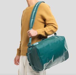 Model with the mini to-go bag slung over their shoulder in color Enfant Précoce Jasper Green