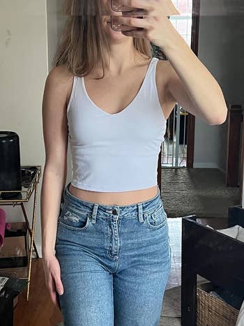 reviewer wearing the white longline sports bra with jeans