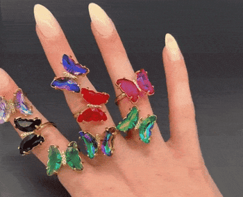 gif of a model with different colored butterfly rings on one hand, spinning them with the other hand