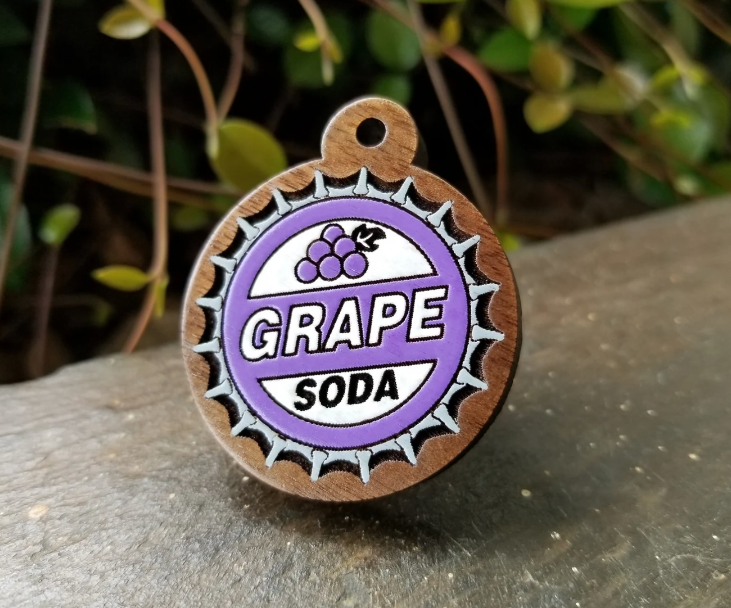 a wooden pet tag with an illustration of the grape soda pin from up