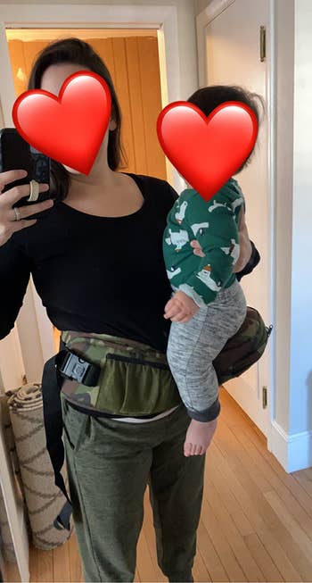 reviewer showing how the carrier wraps around their waist and make it easy to hold a baby