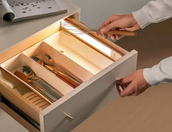 Model pulling open a drawer lit up with a light from the inside 