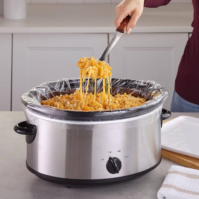 a model scooping mac and cheese out of a lined crockpot