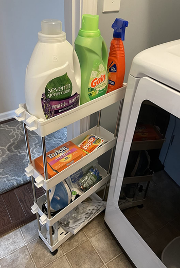 a reviewer photo of the cart pulled out and filled with laundry supplies 