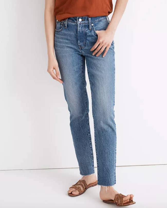Model is wearing mid rise denim jeans, and sandals