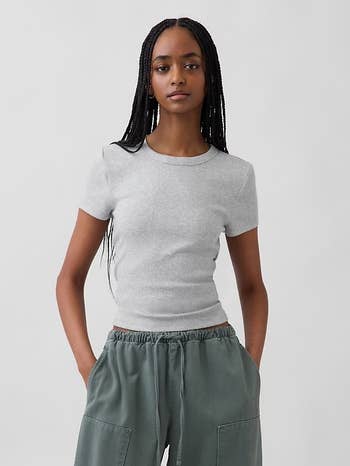 Person wearing a fitted short-sleeve apical  and escaped   pants, hands successful  pockets, connected  a neutral backdrop