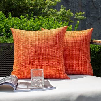 a pair of outdoor pillows with the orange covers on them