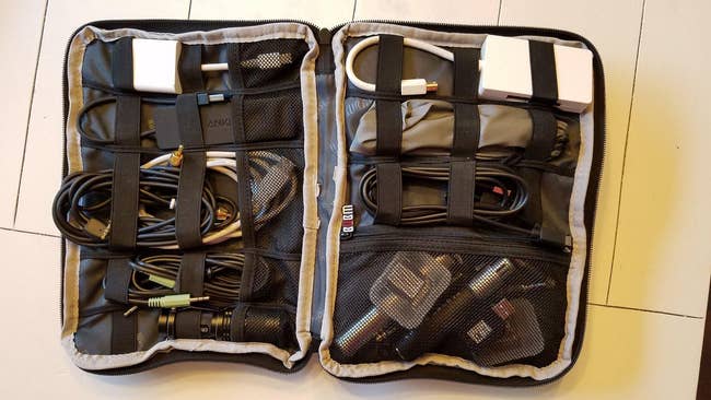 Open travel organizer with neatly arranged electronic cables and chargers in mesh pockets