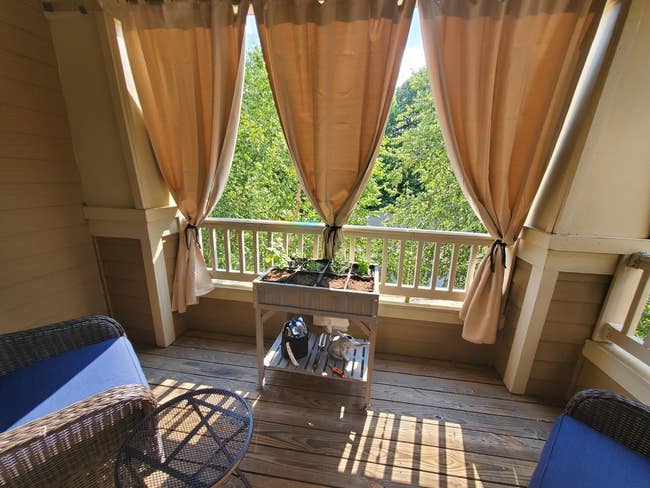 An outdoor patio with a seating area, curtains, and a view of trees, set for a shopping feature