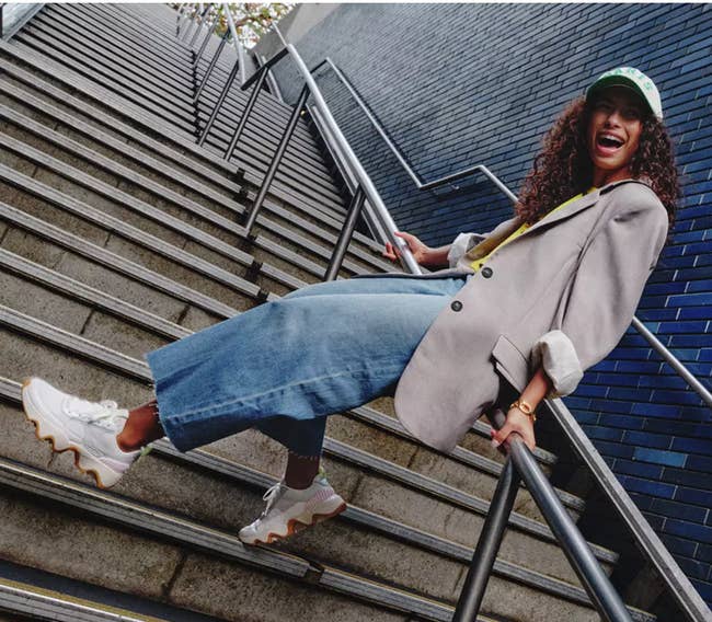 model leans connected stairs with achromatic sneakers and scalloped soles