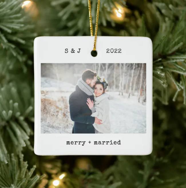 a white square ornament with the initials and date of a couple on the top, a photo of them in the middle, and merry + married on the bottom