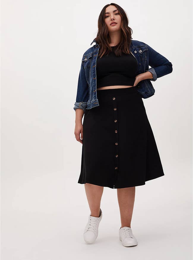 plus-size model wearing the black knee-length skirt with brown buttons down the center