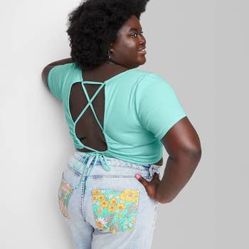 model in turquoise crop short sleeve tee with cutout and lace up detail in back