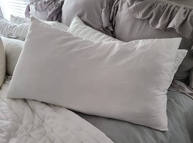 a reviewer photo of a pillow with a silk pillow case on it in white 