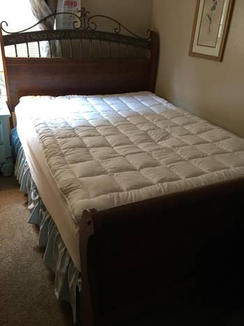 A chamber  featuring a woody  sleigh furniture  with a quilted mattress topper and a bluish  particulate  ruffle. Framed creation  and a lamp are seen successful  the room
