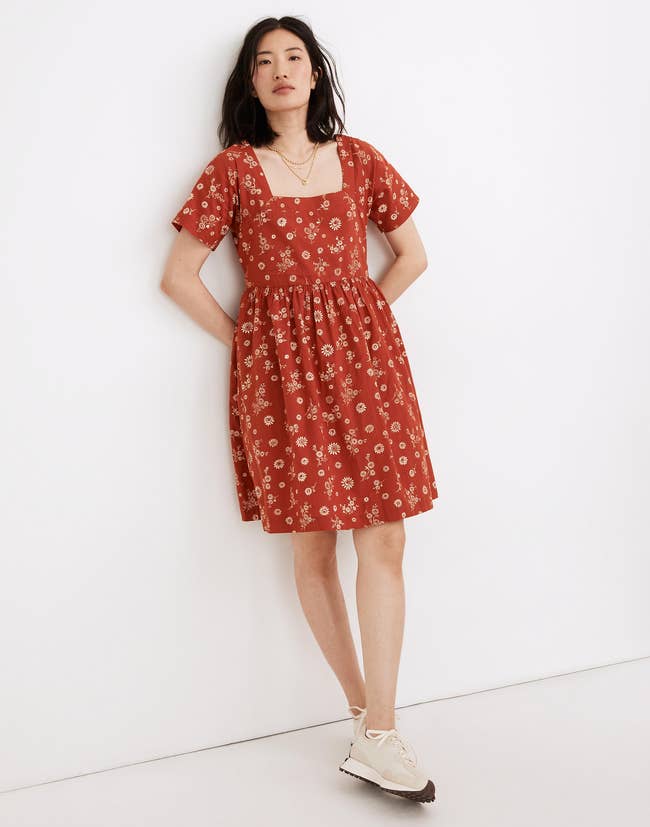 Model in an orange square neck midi dress with short sleeves and ivory floral print 
