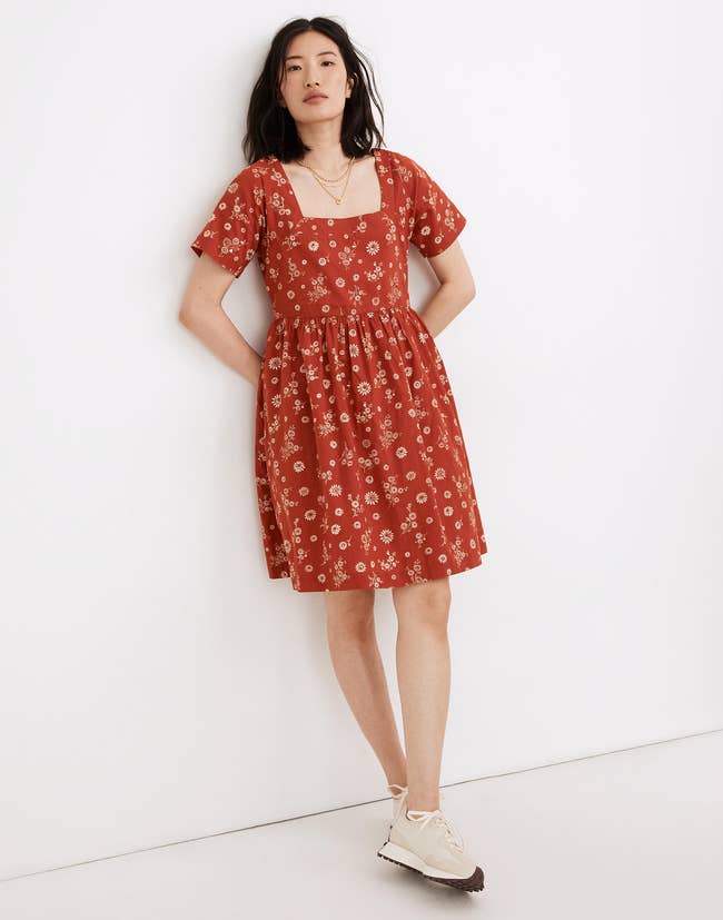 Model in an orange square neck midi dress with short sleeves and ivory floral print 