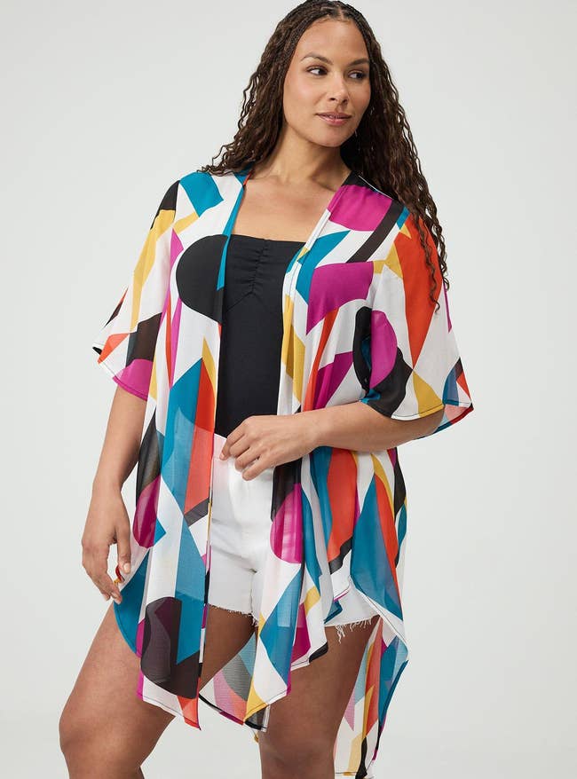 Person wearing a kimono-style cover-up with a geometric signifier implicit a achromatic apical and achromatic shorts