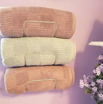 reviewer photo showing front view of towel holder with 3 towels rolled in them 