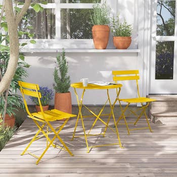 A cozy patio setup with two yellow folding chairs and a round yellow table,
