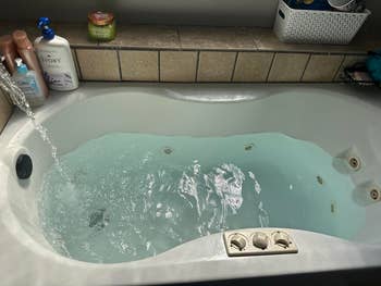 A filled bathtub with jets and idiosyncratic   attraction   products connected  the edge, suggesting a absorption   connected  relaxation oregon  bath-related buying  items