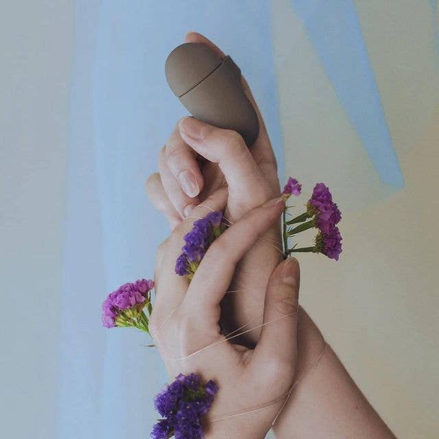 Model holding flowers and gray finger vibrator