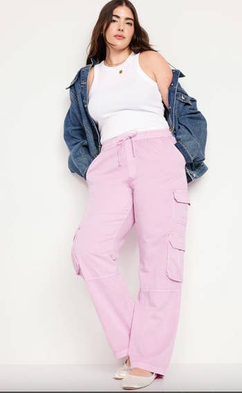 Model wearing pink cargo pants, white tank top, and denim jacket off-shoulder