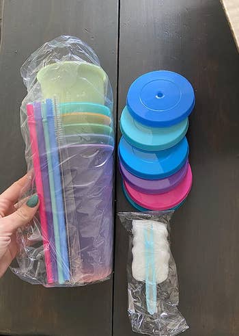 A set of cups in various pastel colors with included lids and straws 