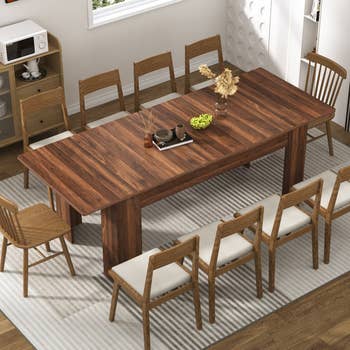 A modern eating country with a agelong woody table, 8 chairs, and a centerpiece of dried flowers, suggesting a mounting for location décor shopping