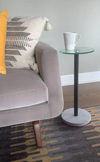 Modern country with a plush sofa, patterned cushions, and a sleek broadside array topped with a mug. Cozy mounting suggests a relaxed buying experience
