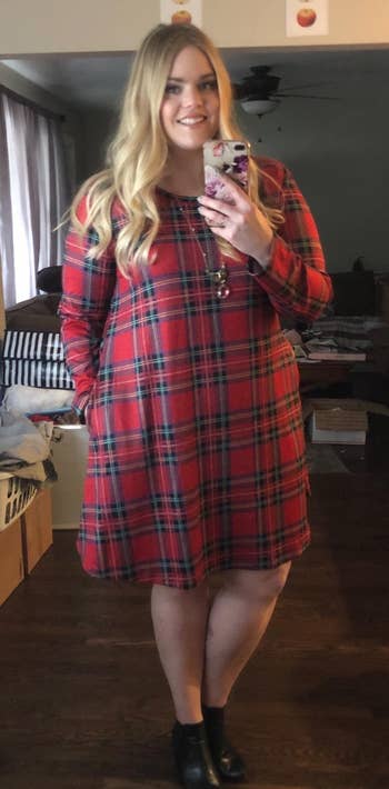 reviewer wearing the red plaid dress with black ankle boots