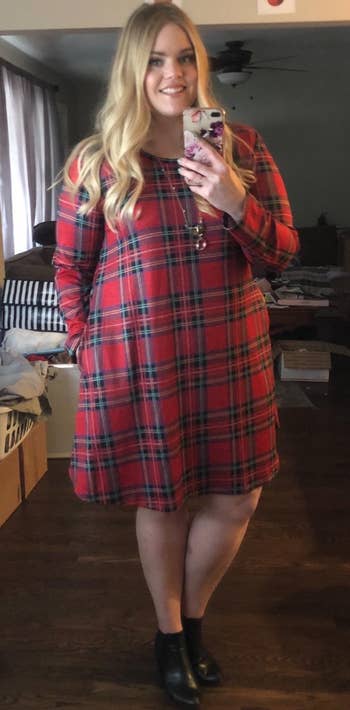 reviewer wearing the red plaid dress with black ankle boots