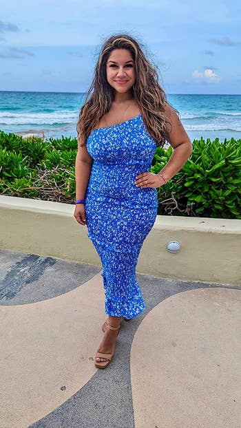 a reviewer wearing the bright blue floral dress