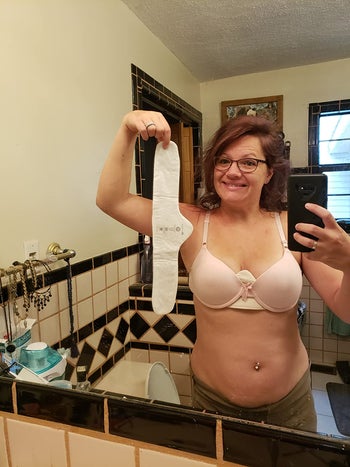 reviewer smiling holding up their bra liner