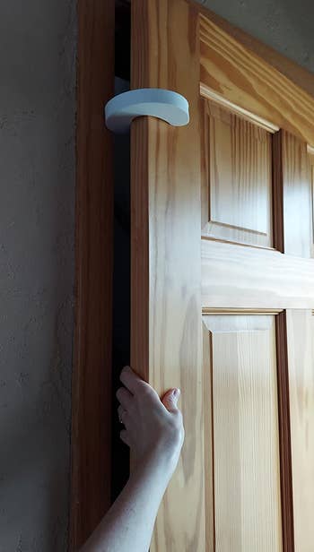 a reviewer with a pinch guuard installed near the top of the door and their hand in the gap created 