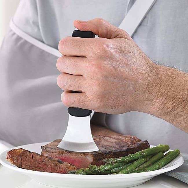Model using a vertical black gripper on a curved blade cutting steak 