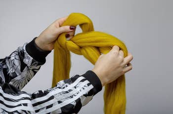 hands pulling a giant knot through yellow yarn