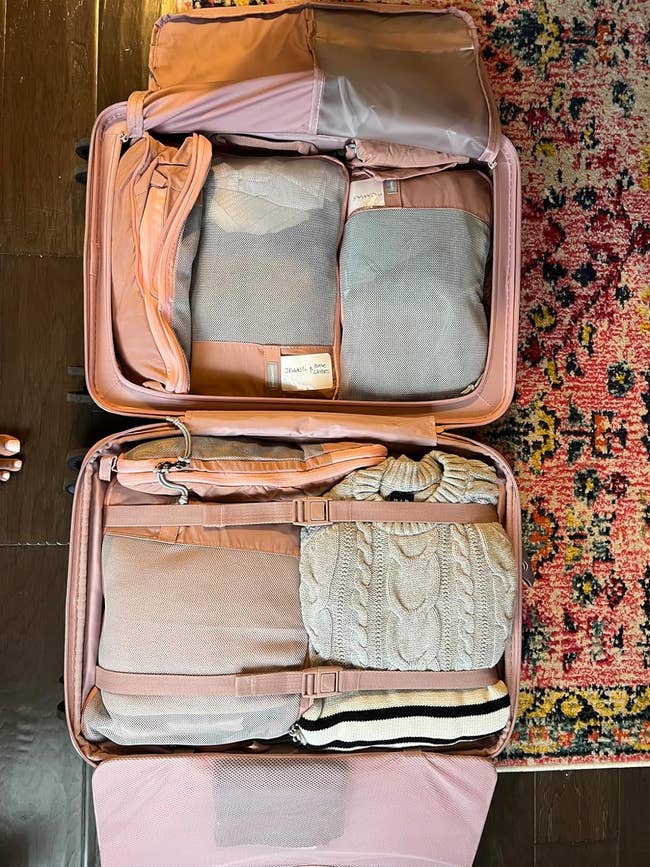 reviewer's open suitcase with clothes packed in compression cubes
