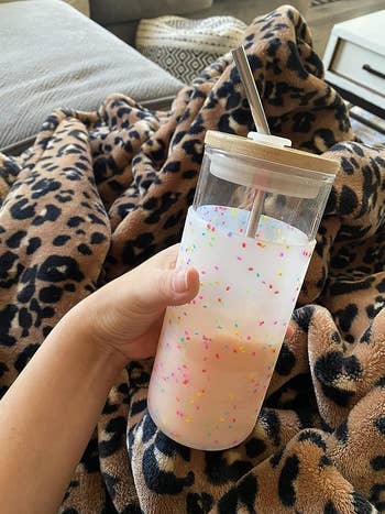 a reviewer holding a glass tumbler with a colorful confetti design on it