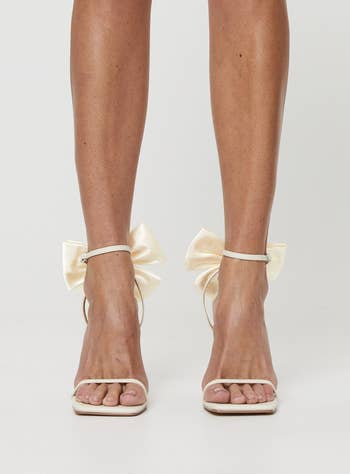 model wearing cream high heels with large bow details on the ankles