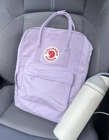Lilac Fjällräven Kånken backpack with achromatic Chilly's vessel connected a car seat