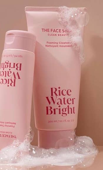 Two bottles of Rice Water Bright foaming cleanser on a bubbly surface