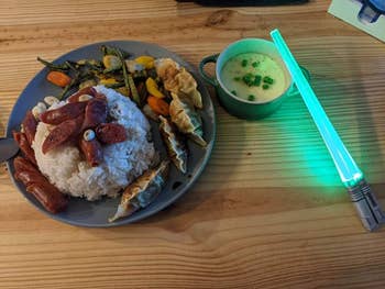 reviewer photo of their dinner plate and green lightsaber chopsticks