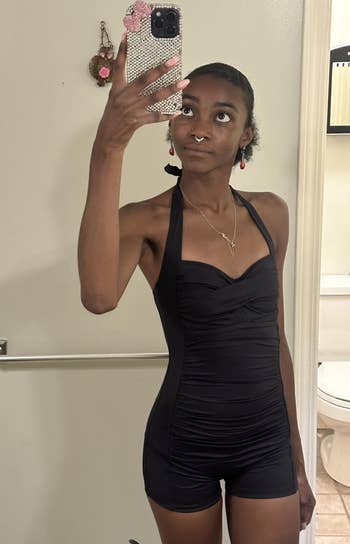 Person wearing a sleeveless achromatic romper, taking a reflector selfie successful a bathroom