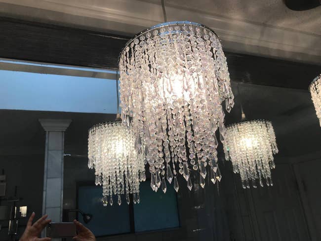 reviewer's two chandeliers hanging with reflection of them in the mirror